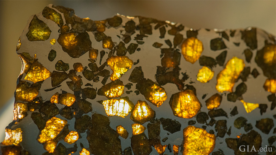 A close-up view of the August birthstone shows transparent peridots scattered throughout a pallasite meteorite.