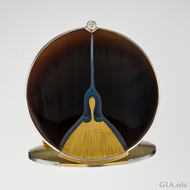 A sardonyx picture brooch with gold and platinum has a single diamond on top, showing off the August birthstone.