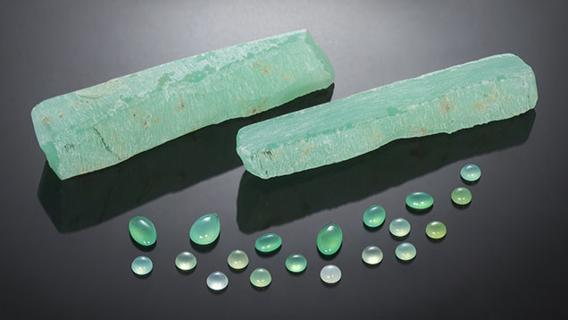Figure 1. Two pieces of rough chrysoprase with several polished stones. The cabochons range from 0.77 to 2.15 ct. Photo by Nuttapol Kitdee; courtesy of John Wibberley, Chrysoprase Australia. Figure 1. Two pieces of rough chrysoprase with several polished stones. The cabochons range from 0.77 to 2.15 ct. Photo by Nuttapol Kitdee; courtesy of John Wibberley, Chrysoprase Australia.