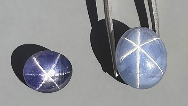 Figure 3. Exceptional star sapphires from Nivithigala, Sri Lanka, viewed in sunlight: a 7.45 ct purple color-change star sapphire (left) and a 19.74 ct light grayish blue star sapphire exhibiting an extraordinarily sharp and distinct star (right). Photo by Jennifer Stone-Sundberg; courtesy of Dudley Blauwet Gems.