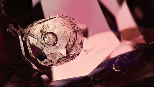 A mobile bubble floating in a cavity in spinel observed under diffused transmitted light. The nature of the substance inside the cavity remains a mystery. Photomicrograph by E. Billie Hughes; field of view ~3.5 mm.