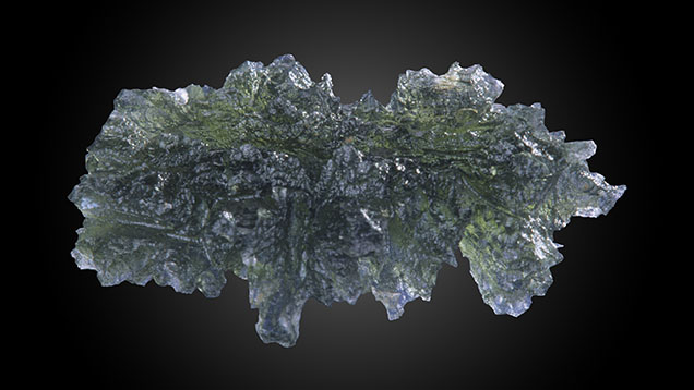 Figure 1. A true collector’s item, this 32.06 mm long ornate leaf-shaped olive green moldavite is from the Besednice strewn field in the Czech Republic. Possessing unbroken spires and undamaged surfaces, this pristine condition is rare. Photo by Maha Calderon. Figure 1. A true collector’s item, this 32.06 mm long ornate leaf-shaped olive green moldavite is from the Besednice strewn field in the Czech Republic. Possessing unbroken spires and undamaged surfaces, this pristine condition is rare. Photo by Maha Calderon.
