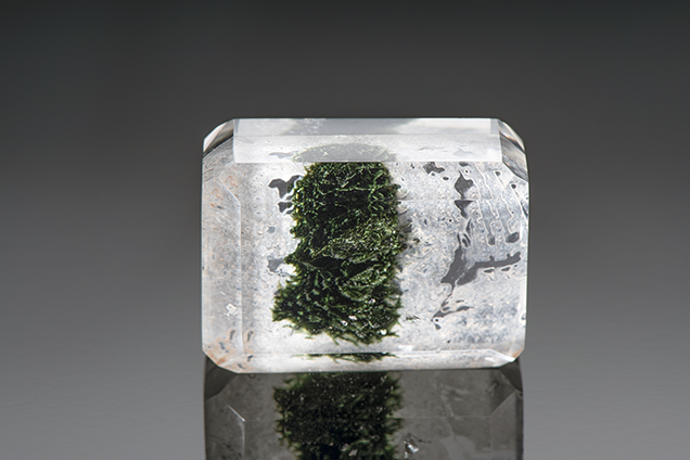 Assembled block of polished quartz encloses fractures filled with a green resin.