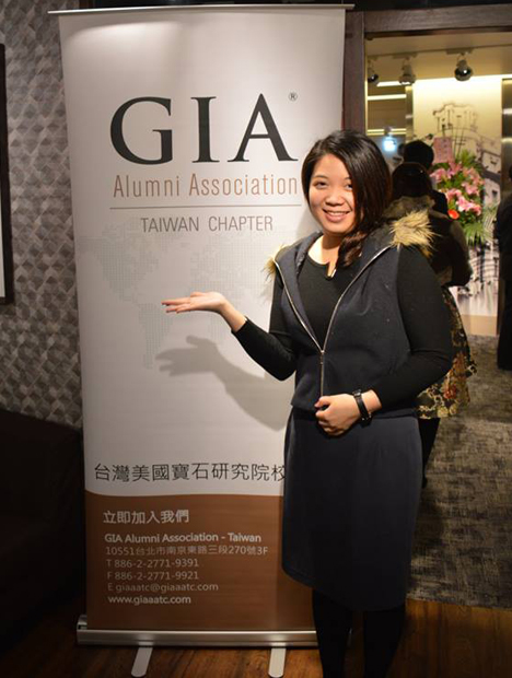 活动现场一位站在 GIA 旗帜前的女士。 活动现场一位站在 GIA 旗帜前的女士。
