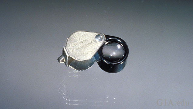 A 10x loupe sits on a grey background. A 10x loupe sits on a grey background.