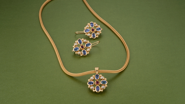 Matching pendant and earrings feature four oval tanzanites that alternate with pearls around a ruby center.