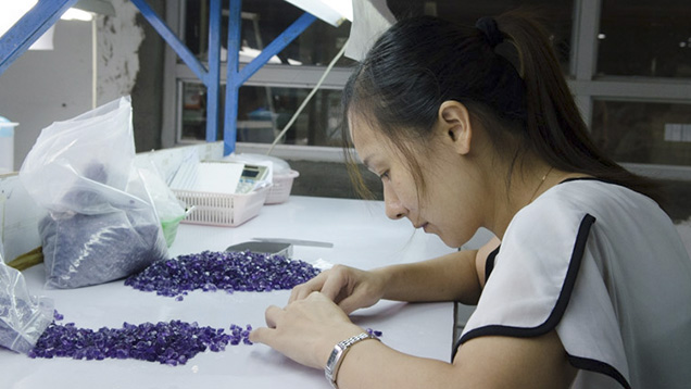 Chinese woman examines rough gemstones Chinese woman examines rough gemstones