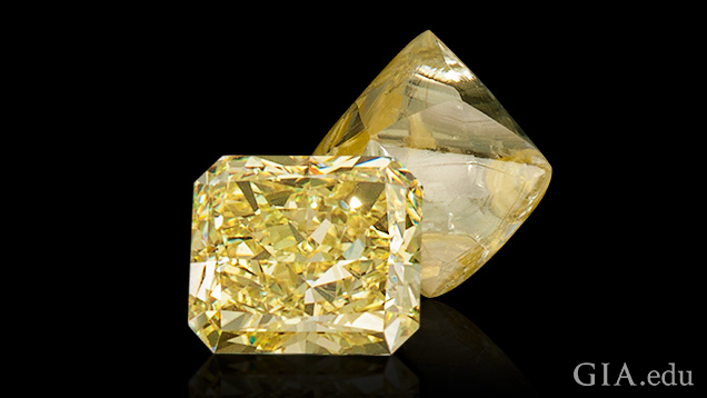 A polished and cut yellow diamond sits in front of a rough yellow diamond. A polished and cut yellow diamond sits in front of a rough yellow diamond.