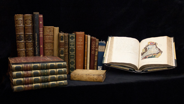 A sampling of beautiful rare books displayed in a row and in several piles – one with its pages open. A sampling of beautiful rare books displayed in a row and in several piles – one with its pages open.