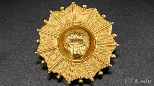 Gold pendant features a lion head in the middle; the frame around it is separated into sections with each section displaying a letter that taken together spell out ROMA ETERNA. Gold pendant features a lion head in the middle; the frame around it is separated into sections with each section displaying a letter that taken together spell out ROMA ETERNA.