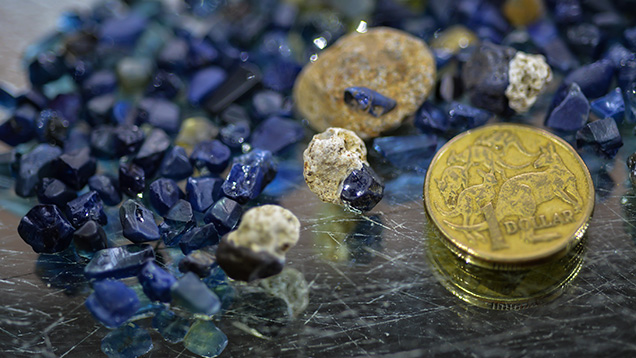 Sapphire rough and host rock. Some of these sapphire crystals still have host rock attached, which is fairly rare in Australia. Photo by Vincent Pardieu/GIA.. サファイアの原石と母岩