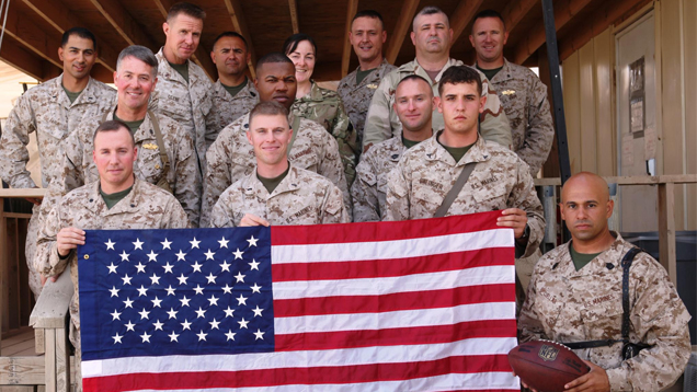 Diaz stands with 13 fellow Marines as they pose in camouflage with the American flag. Diaz stands with 13 fellow Marines as they pose in camouflage with the American flag.