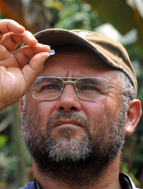Close up shot of Manuel Diaz as he holds a blue spinel up in front of his eyes. Close up shot of Manuel Diaz as he holds a blue spinel up in front of his eyes.