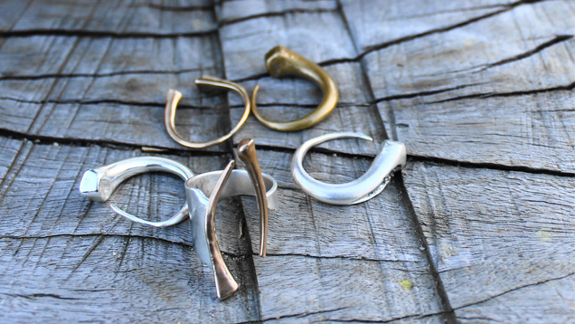 Earrings are displayed on a piece of wood and rings sit in the foreground.Earrings are displayed on a piece of wood and rings sit in the foreground.
