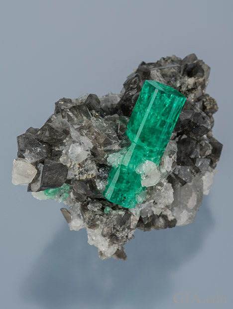 Emerald Crystal in Calcite. Emerald crystal in white and smoky calcite from the Coscuez Mine in Colombia. Courtesy of Bill Larson. Photo: Robert Weldon/GIA