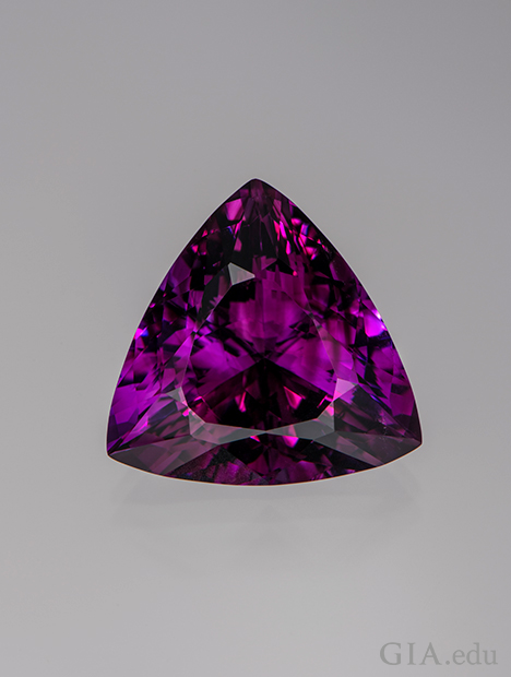 A triangle shaped piece of purple-red amethyst. A triangle shaped piece of purple-red amethyst.