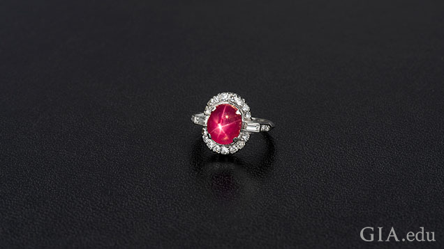 Oval ruby cabochon framed with diamonds.