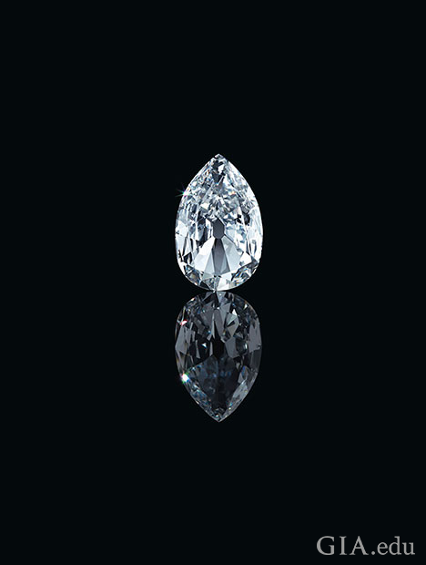 A large pear shaped diamond sits on a black background with its reflection in front of it.