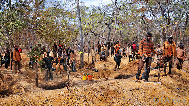 A large group of miners work around small digs. A large group of miners work around small digs.
