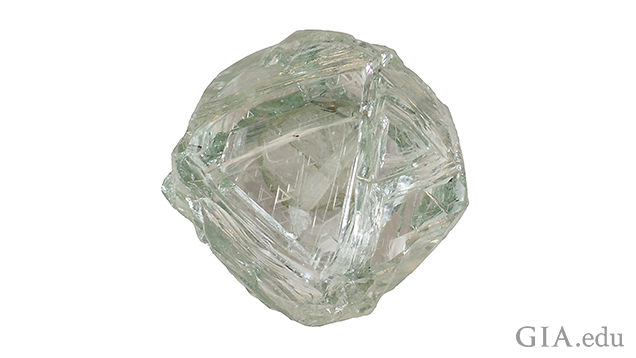 A piece of diamond rough with green body color and triangular etchings on the surface. A piece of diamond rough with green body color and triangular etchings on the surface.