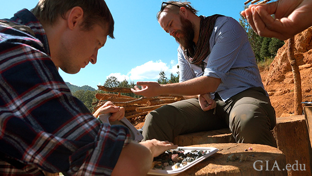 Two men sort through gem gravel on site. Two men sort through gem gravel on site.