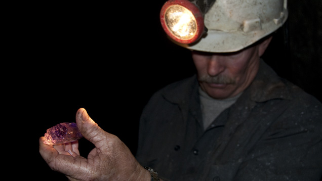 Kunzite. This miner is handling a kunzite crystal at the Oceanview Mine in Pala, California, for the very first time since its formation. - Brendan Laurs