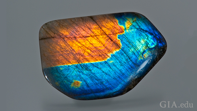 This predominately blue gem has a large orange area in the top left and patches of green and orange elsewhere. This predominately blue gem has a large orange area in the top left and patches of green and orange elsewhere.