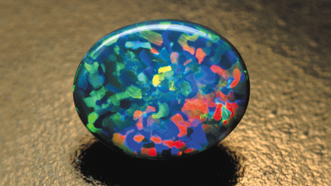 Black-Opal-41365-1280x720.jpg. This black opal has red, blue, and green play-of-color in a jigsaw pattern. Photo courtesy Cody Opal.