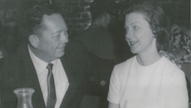 A man and woman sit at a restaurant table gazing at one another.