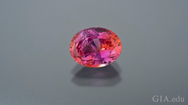 A band of pink in the center is bordered by orange on each side in this oval Padparadscha sapphire.