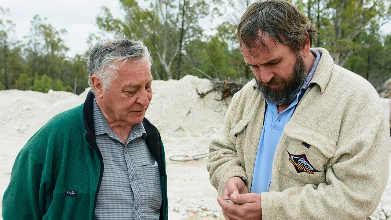DSC_1446_185783-1280x720.jpg. Australian gemstone miner, cutter, and dealer Terry Coldham and opal miner Kim examine a rough black opal while they discuss the Australian opal industry. Photo by Andrew Lucas/GIA.
