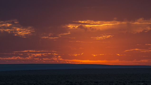 The orange glory of the setting sun hovers above a rich high-desert landscape. - Robert Weldon The orange glory of the setting sun hovers above a rich high-desert landscape. - Robert Weldon