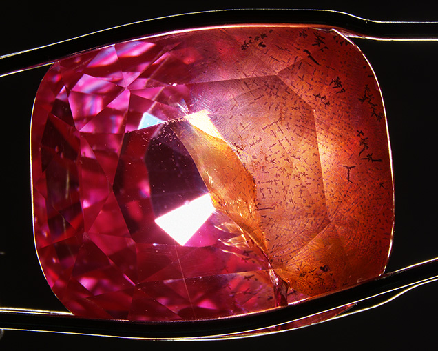 Pink-orange synthetic sapphire contains large fractures with orange staining. Pink-orange synthetic sapphire contains large fractures with orange staining.