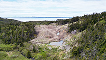 alt="Figure 2. View of the amethyst-bearing trench looking west-southwest into Placentia Bay. The vein is exposed in the right side of the trench, and overburden is displaced to the left. Aerial drone photo by Philippe Belley. alt="Figure 2. View of the amethyst-bearing trench looking west-southwest into Placentia Bay. The vein is exposed in the right side of the trench, and overburden is displaced to the left. Aerial drone photo by Philippe Belley.