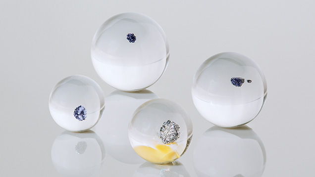 Figure 1. Weighing between 3.07 and 10.53 ct, these four small transparent colorless spheres of rock crystal quartz each hosted an opaque black inclusion (one sphere contained two inclusions). Photo by Annie Haynes. Figure 1. Weighing between 3.07 and 10.53 ct, these four small transparent colorless spheres of rock crystal quartz each hosted an opaque black inclusion (one sphere contained two inclusions). Photo by Annie Haynes.