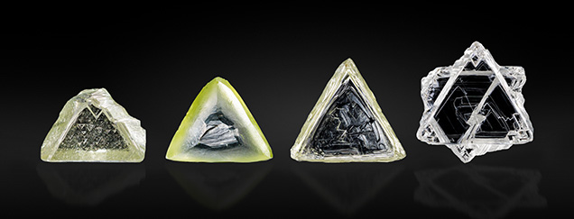 Four triangular crystals of varying colors and textures, displayed against a black background. Four triangular crystals of varying colors and textures, displayed against a black background.
