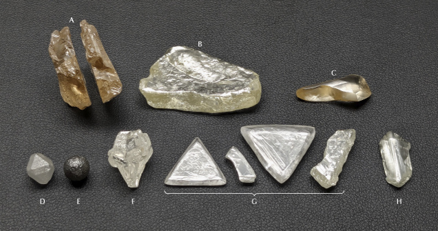 A collection of various mineral specimens, including crystalline shapes and different textures, arranged on a dark background.