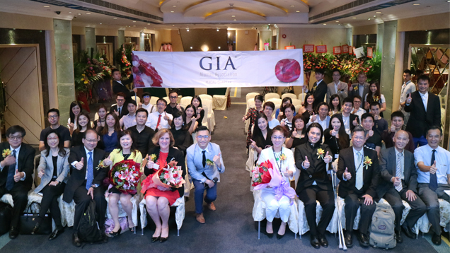 マカオ支部の創設を祝うために集まり写真撮影をする大勢の人々。 GIAの旗がその背後に掲げられている。