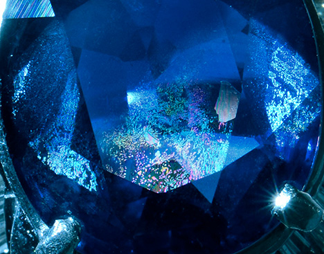 A blue sapphire features large iridescent healed fissures. A blue sapphire features large iridescent healed fissures.