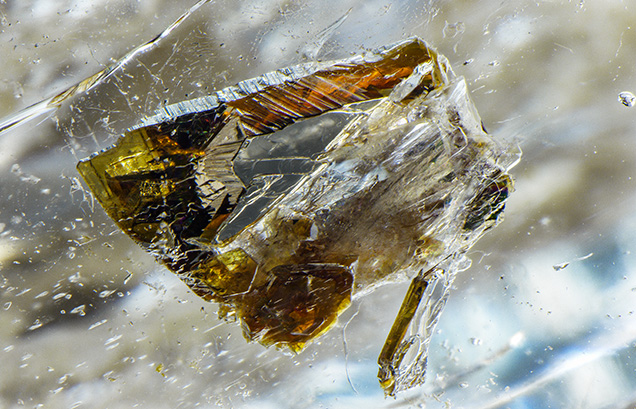 Strong brownish orange and yellow dichroism can be seen in this phlogopite mica crystal inclusion.