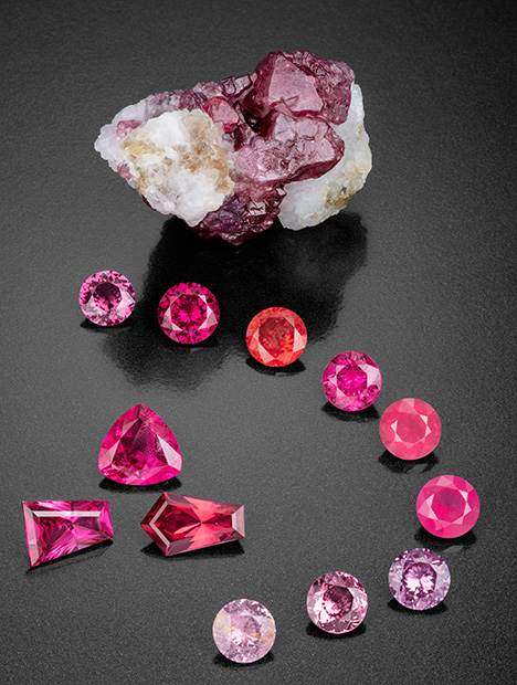 Figure 2. This remarkable suite of spinel gems faceted by Bill Vance shows a wonderful range of color and transparency. The 232.9 ct rough mineral specimen gives clues to the crystal’s origin, with remnants of the marble host rock preserved. The faceted Figure 2. This remarkable suite of spinel gems faceted by Bill Vance shows a wonderful range of color and transparency. The 232.9 ct rough mineral specimen gives clues to the crystal’s origin, with remnants of the marble host rock preserved. The faceted