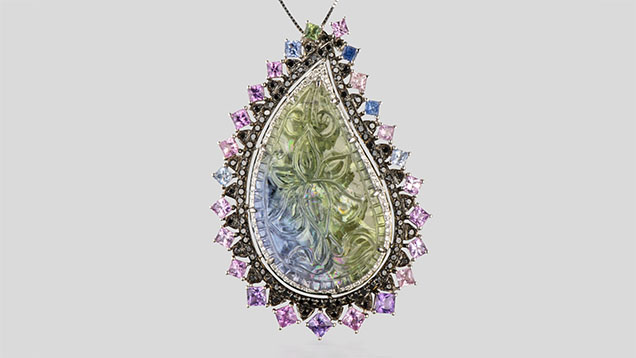 Figure 2. An 18K white gold pendant containing a paisley-shaped unheated tanzanite with a lotus blossom carving, surrounded by pavé-set black diamonds and pink and purple princess-cut Sri Lankan sapphires. The total weight of the diamonds is 1.00 carats, and the colored stones total 23.40 carats. Photo by Robert Weldon; courtesy of YNY Jewels Inc. Figure 2. An 18K white gold pendant containing a paisley-shaped unheated tanzanite with a lotus blossom carving, surrounded by pavé-set black diamonds and pink and purple princess-cut Sri Lankan sapphires. The total weight of the diamonds is 1.00 carats, and the colored stones total 23.40 carats. Photo by Robert Weldon; courtesy of YNY Jewels Inc.