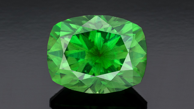 Figure 4. A 5.34 ct vivid green modified cushion-cut Russian demantoid garnet displaying horsetail inclusions. Photo by Robert Weldon; courtesy of Tsarina Jewels. Figure 4. A 5.34 ct vivid green modified cushion-cut Russian demantoid garnet displaying horsetail inclusions. Photo by Robert Weldon; courtesy of Tsarina Jewels.