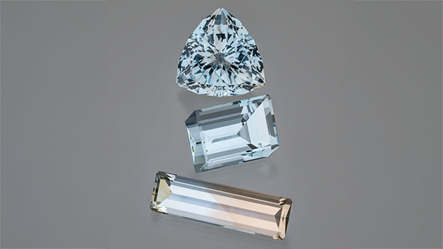 Figure 2. Exceptionally large and clean blue and bicolor topaz from the Volyn deposit. The blue triangular cut is 113.86 ct, the middle blue cube cut is 87.82 ct, and the blue and golden bicolor rectangular cut is 55.70 ct. Photo by Robert Weldon; courtesy of Dudley Blauwet Gems. Figure 2. Exceptionally large and clean blue and bicolor topaz from the Volyn deposit. The blue triangular cut is 113.86 ct, the middle blue cube cut is 87.82 ct, and the blue and golden bicolor rectangular cut is 55.70 ct. Photo by Robert Weldon; courtesy of Dudley Blauwet Gems.