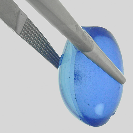 Synthetic star cabochon showing shallow coloration with a colorless circular area of repolishing. Synthetic star cabochon showing shallow coloration with a colorless circular area of repolishing.