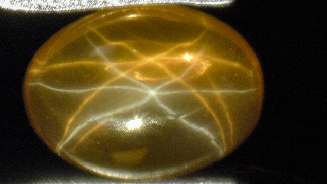 Yellow-orange synthetic sapphire with a white star and a yellow-orange star Yellow-orange synthetic sapphire with a white star and a yellow-orange star