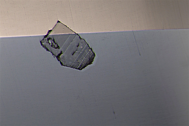 Surface-breaking crystal seen in red spinel. Surface-breaking crystal seen in red spinel.