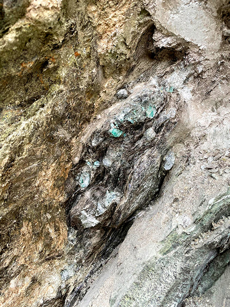 Figure 2. An emerald pocket at the reaction zone between the pale pegmatite intrusion (bottom right) and ultramafic greenish rock (top left). The emeralds are encrusted in dark mica crystals. Photo by Matthew Allen; field of view approximately 50 cm. Figure 2. An emerald pocket at the reaction zone between the pale pegmatite intrusion (bottom right) and ultramafic greenish rock (top left). The emeralds are encrusted in dark mica crystals. Photo by Matthew Allen; field of view approximately 50 cm.