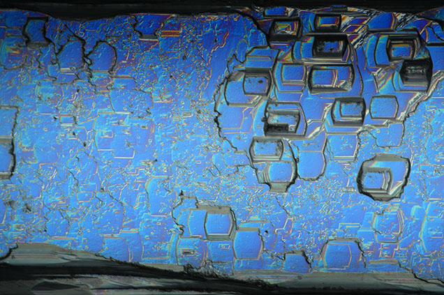 Figure 3. Aquamarine viewed with differential interference contrast filters. Hexagonal, pseudorectangular, and uneven etch features exist on every prismatic face and run the length of the crystal. Photomicrograph by Rhiana Henry; field of view 2.88 mm.