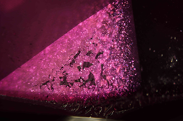Reflective silk inclusions in the natural sapphire seed are visible behind a coarse flux fingerprint in the synthetic ruby overgrowth. Reflective silk inclusions in the natural sapphire seed are visible behind a coarse flux fingerprint in the synthetic ruby overgrowth.